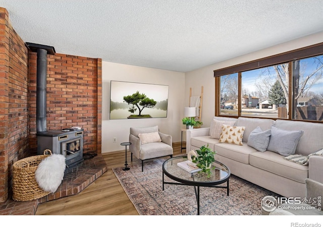 living area with a wood stove, a textured ceiling, and light wood finished floors