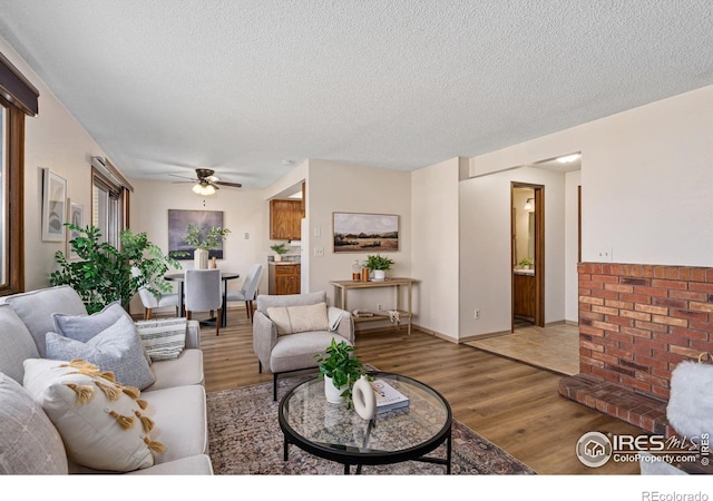 living area with light wood-style floors, ceiling fan, and a textured ceiling