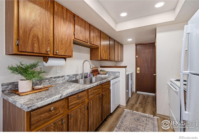 kitchen with white appliances, light wood-style floors, a sink, and brown cabinetry