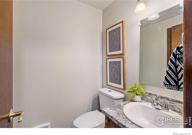 half bath featuring toilet, visible vents, and vanity