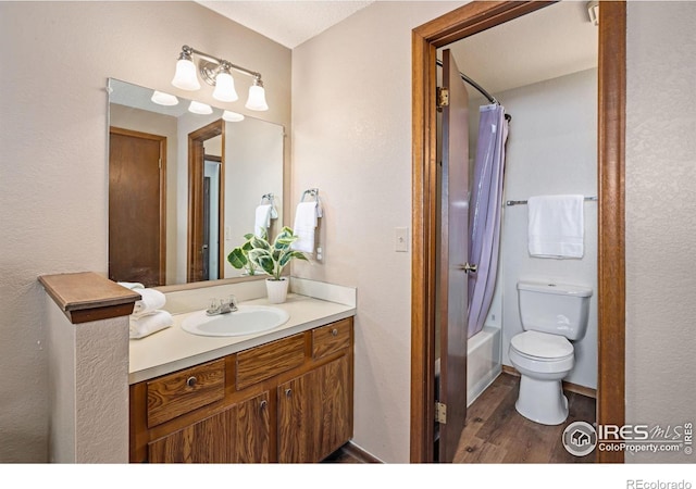 full bath with shower / bath combo, baseboards, toilet, wood finished floors, and vanity