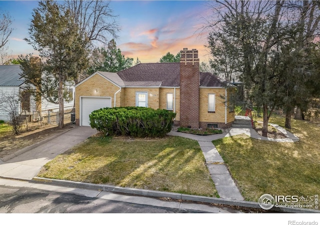 view of front of property featuring a front yard, driveway, a chimney, and brick siding