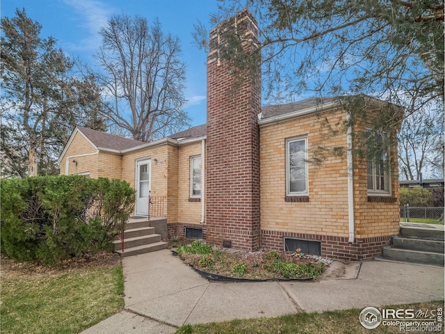 view of front of home with a chimney and brick siding