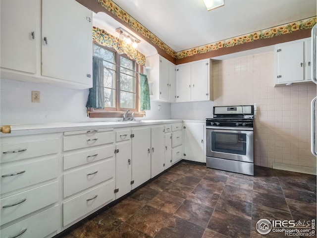 kitchen with white cabinets, light countertops, stainless steel range with gas stovetop, and tile walls