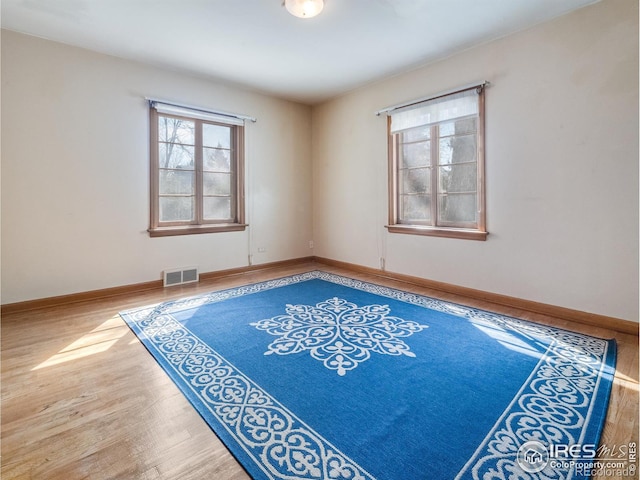 unfurnished room with baseboards, visible vents, and wood finished floors