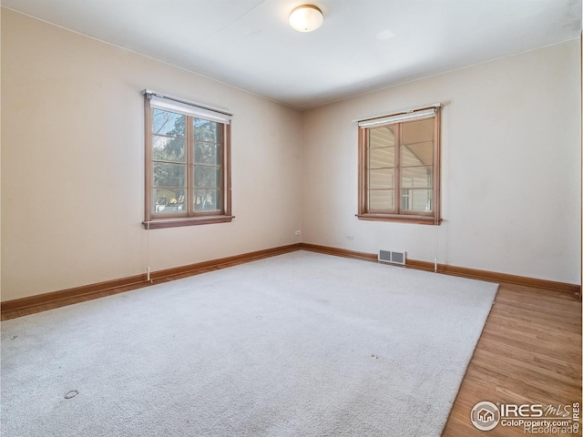 unfurnished room featuring visible vents, light wood-style flooring, and baseboards