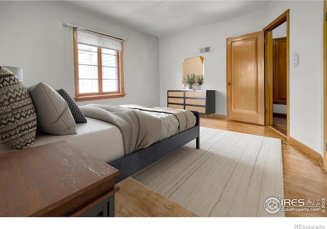 bedroom with baseboards, visible vents, and light wood-style floors