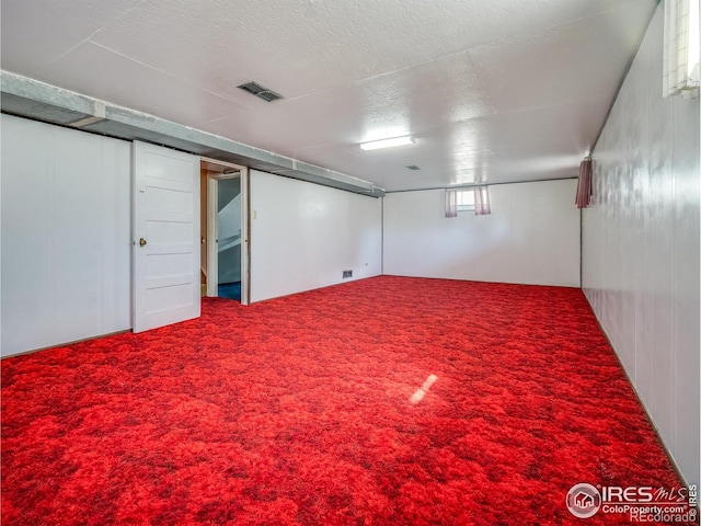 below grade area with carpet, visible vents, and a textured ceiling