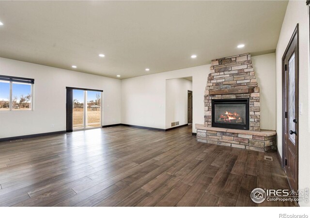 unfurnished living room featuring recessed lighting, visible vents, dark wood-type flooring, and a stone fireplace