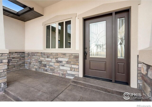 doorway to property featuring stone siding and stucco siding