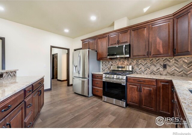 kitchen with stainless steel appliances, light stone countertops, backsplash, and dark wood-style flooring