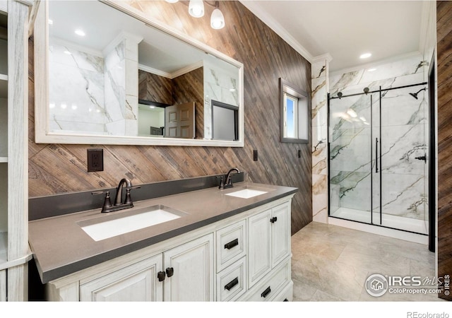 full bath featuring crown molding, double vanity, a marble finish shower, and a sink