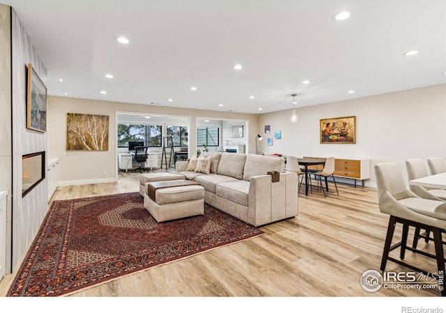 living area featuring light wood-style floors, recessed lighting, and a fireplace