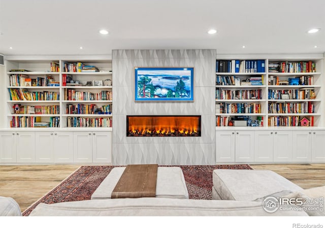 living area with a large fireplace, wood finished floors, and recessed lighting