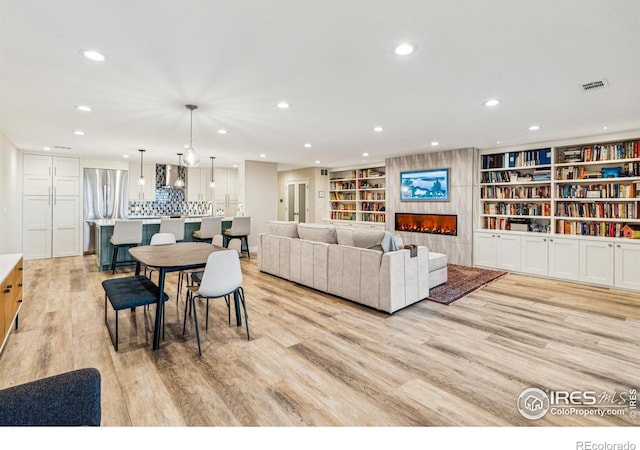 dining space with light wood-style floors, visible vents, a tiled fireplace, and recessed lighting