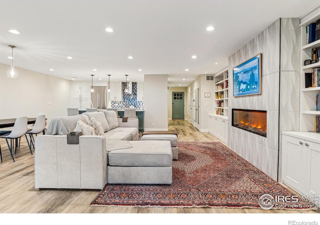 living area with light wood-style floors, recessed lighting, and a large fireplace