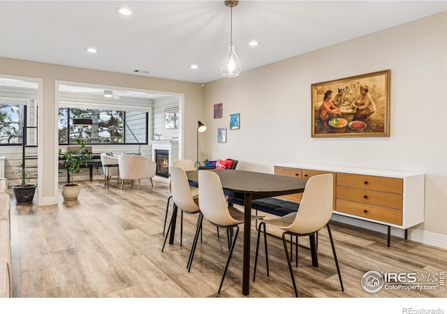 dining area with light wood-style floors, a glass covered fireplace, baseboards, and recessed lighting