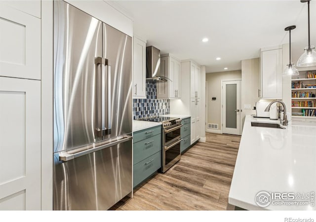 kitchen featuring a sink, visible vents, appliances with stainless steel finishes, wall chimney range hood, and light wood finished floors