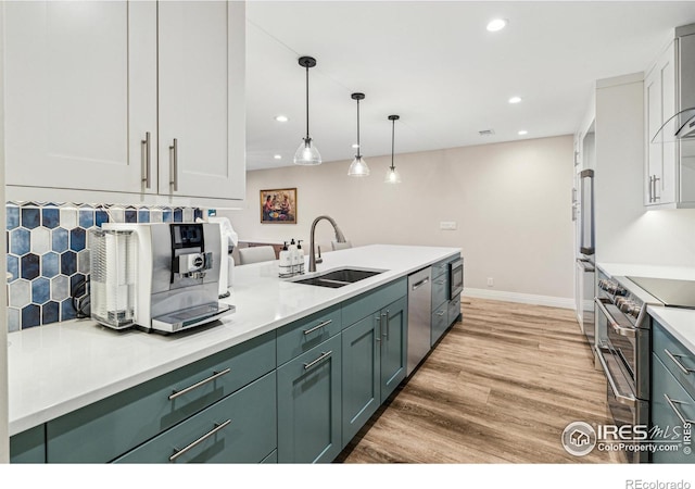 kitchen with light wood finished floors, stainless steel appliances, light countertops, backsplash, and a sink