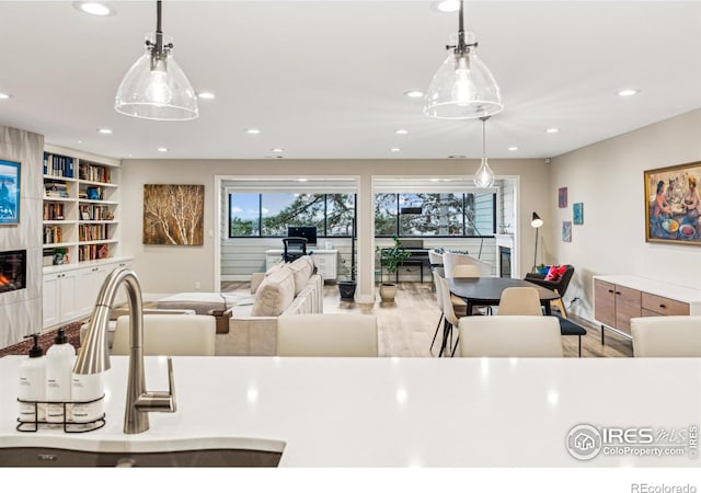 kitchen with pendant lighting, recessed lighting, a large fireplace, and wood finished floors