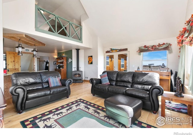 living room with visible vents, high vaulted ceiling, wood finished floors, and a wood stove