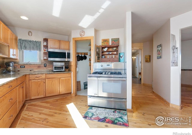 kitchen with light wood finished floors, baseboards, decorative backsplash, stainless steel appliances, and open shelves