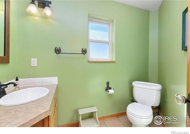 half bathroom with tile patterned flooring, baseboards, vanity, and toilet