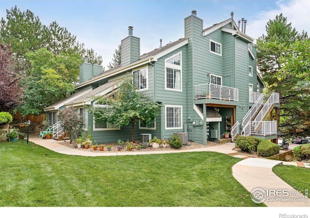 back of property with stairs, a chimney, central AC, and a yard