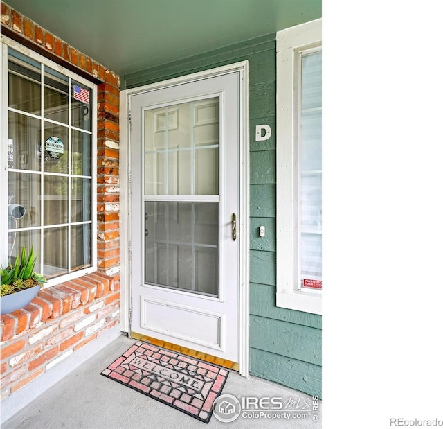 entrance to property featuring a porch and brick siding