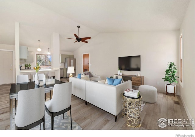 living area featuring a ceiling fan, vaulted ceiling, light wood-style floors, and visible vents