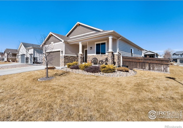 view of front of property featuring stone siding, an attached garage, driveway, and a front lawn