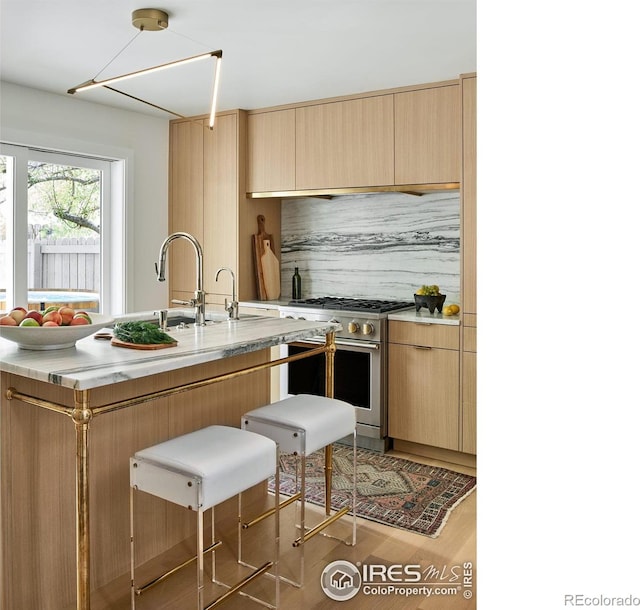 kitchen with light countertops, light brown cabinets, stainless steel stove, and a kitchen breakfast bar