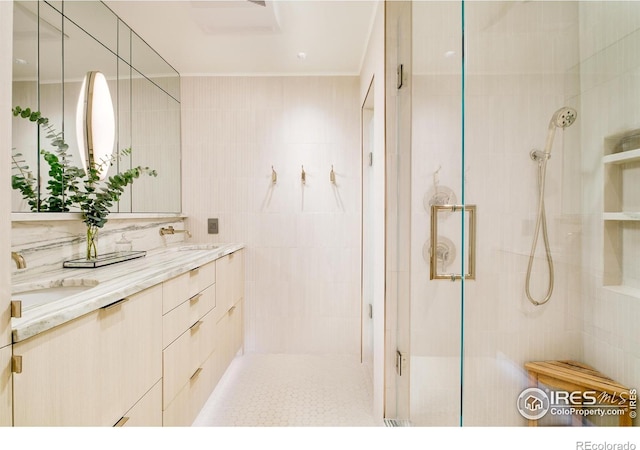 full bath featuring double vanity, a stall shower, ornamental molding, and a sink