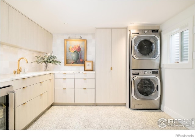 laundry area featuring a sink, laundry area, wine cooler, and stacked washer / drying machine