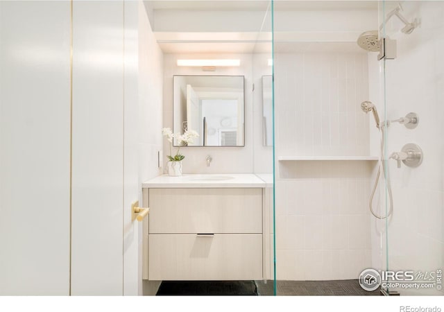 full bathroom featuring tiled shower and vanity