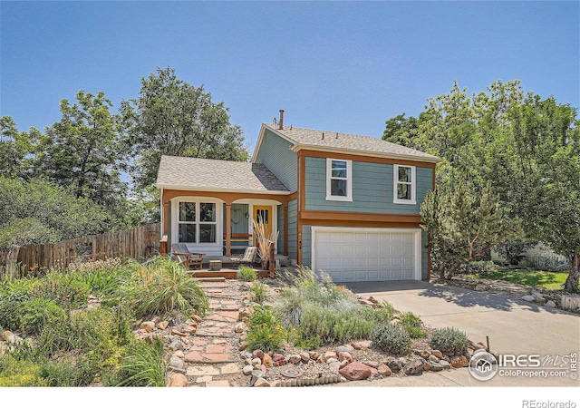 split level home featuring a garage, driveway, and fence