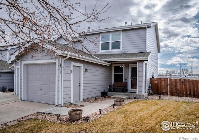 traditional-style home featuring roof with shingles, an attached garage, a front yard, fence, and driveway