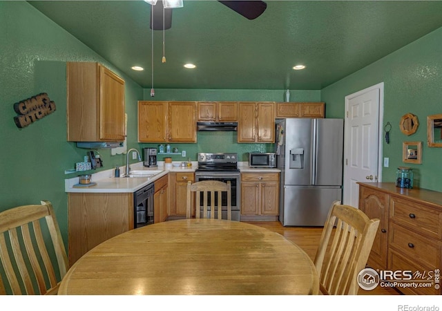 kitchen featuring recessed lighting, under cabinet range hood, stainless steel appliances, a sink, and light countertops