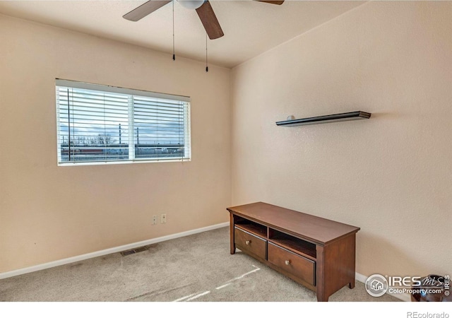 interior space featuring baseboards, visible vents, ceiling fan, and carpet flooring