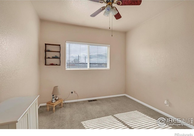 spare room with ceiling fan, a textured wall, carpet floors, visible vents, and baseboards