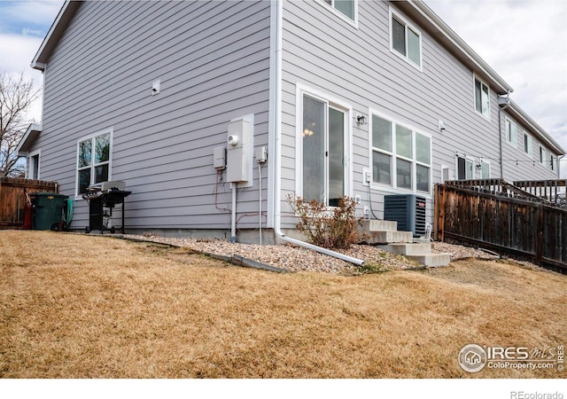 view of side of property featuring a yard, central AC, and fence