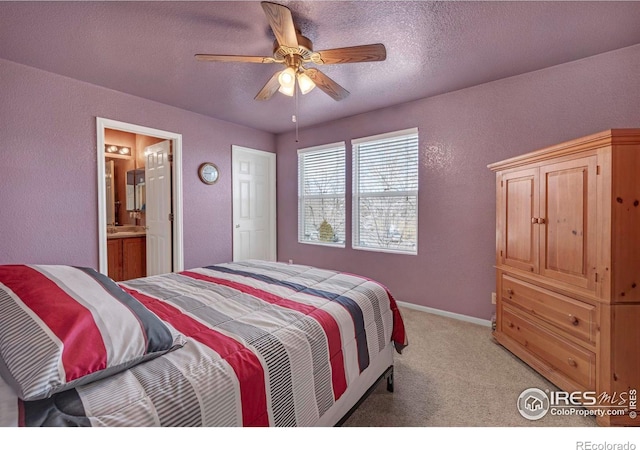 bedroom featuring light colored carpet, a textured wall, connected bathroom, a textured ceiling, and baseboards