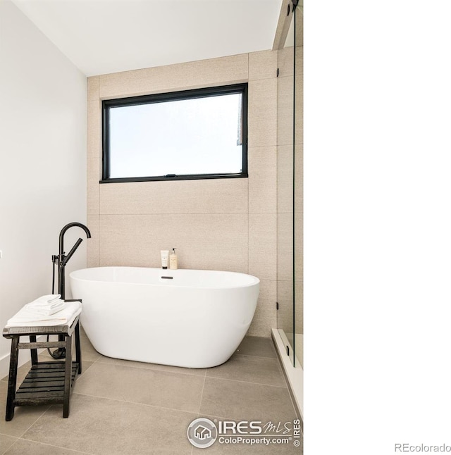 2586 3rd St, Boulder, CO 80304 - bathroom featuring a soaking tub, healthy amount of natural light, tile patterned flooring, a shower with door, and tile walls