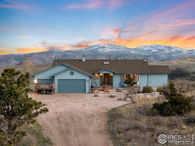 view of front of house with a garage, a mountain view, and dirt driveway