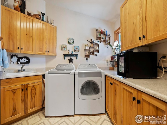 laundry area featuring light floors, cabinet space, a sink, and washing machine and clothes dryer