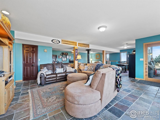 living room featuring stone tile flooring, indoor bar, a textured ceiling, and baseboards