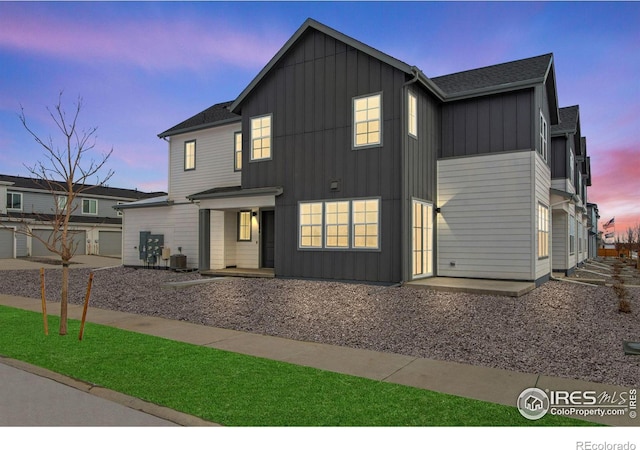 modern inspired farmhouse with driveway, a garage, central AC unit, and board and batten siding