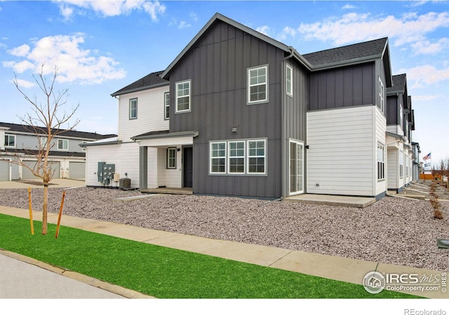 view of front facade featuring board and batten siding, a shingled roof, and central AC unit