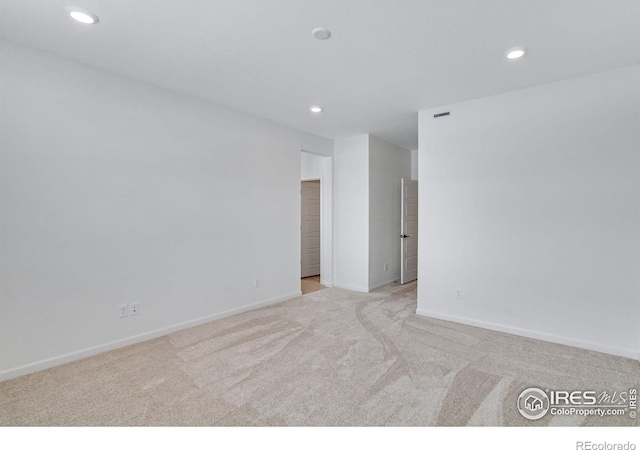 spare room featuring light carpet, baseboards, and recessed lighting