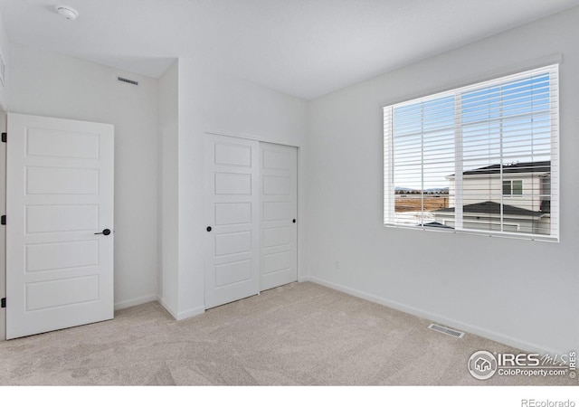 unfurnished bedroom featuring a closet, visible vents, baseboards, and carpet flooring